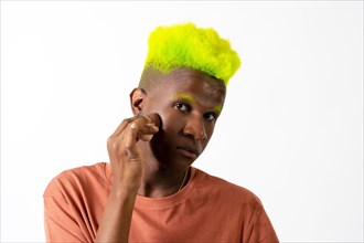 An androgynous black man posing putting on makeup