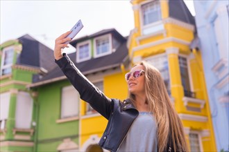 Young blonde with leather jacket taking a selfie with the mobile