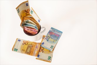 Rolled euro banknotes in a white cup with white background and copy space