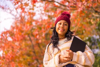 Asian girl in autumn with a tablet in her hand