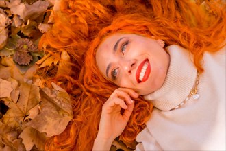 Redhead woman lying on leaves in city park