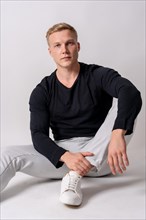 Caucasian blonde model in a black sweater on a white background