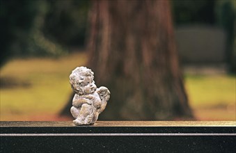 Small angel figure sitting on a gravestone
