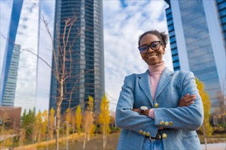 Black ethnic businesswoman or executive wearing glasses standing in a business park