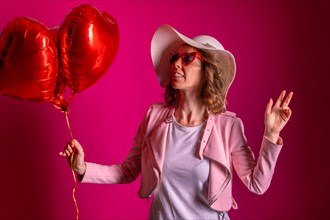 Portrait of a caucasian woman enjoying dancing with a white hat in a nightclub with some heart balloons