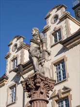 Detail of fountain with a statue of a man in front of an old building in the old town
