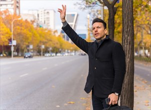 Middle-aged caucasian businessman hailing a taxi raising his hand to go to work