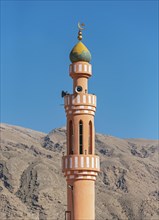 Minaret of Islamic Mosque with mountains in background