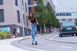 A young brunette woman moving in the city with an electric scooter smiling