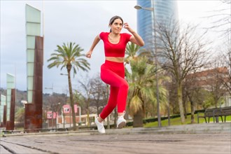 Fit woman in red clothes doing jogging exercises in the city