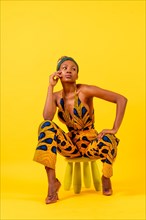 Young African woman in traditional dress on yellow background