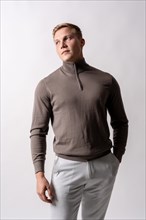 Portrait of an attractive blond german model with brown sweater on a white background