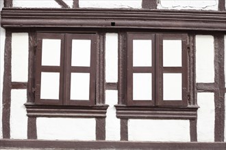 Window shutters closed on a white house wall with half-timbered beams