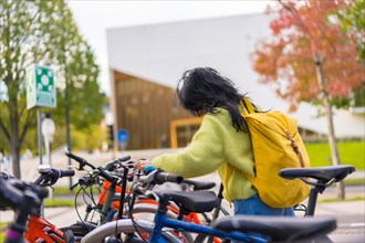 Asian female student parking the bike in college campus
