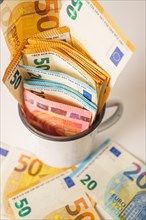 Euro banknotes in a white cup with white background and copy space