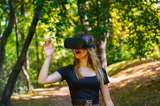 Woman with virtual reality glasses enjoying nature seeing things in the glasses