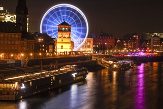 Rhine promenade with castle tower and illuminated Ferris wheel at dusk