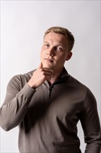 Portrait of a blond german model with a brown sweater on a white background