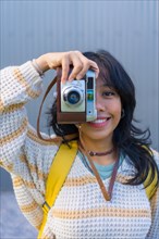 Portrait of a young Asian woman photographing with a vintage photo camera