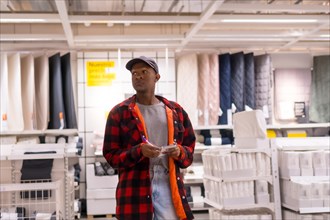 Black ethnic man shopping in a supermarket for carpets and towels