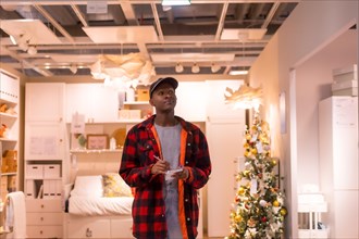 Black ethnic man shopping in a supermarket for almeadas and cushions. christmas shopping