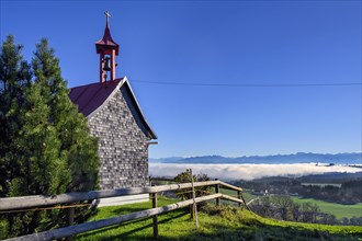 The small chapel of Eschachberg at Blender with a view of the Alps with clouds of mist near Kempten