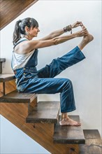 A woman doing stretching exercises on the stairs of her home. Wellbeing concept