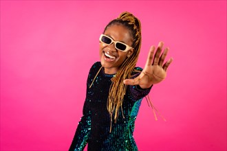 A black ethnic woman with braids dancing at party on a pink background