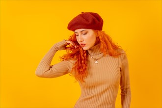 Portrait of red-haired woman in a red beret on a yellow background