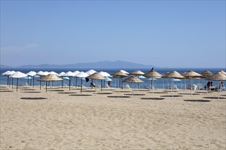 Straw parasols on the sandy beach on the Aegean Sea