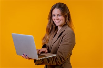 Blue-eyed business woman on a yellow background with a computer