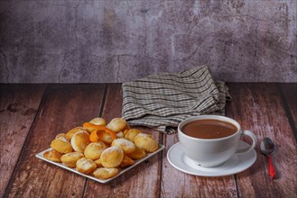 Homemade doughnuts with sugar and hot chocolate in a white mug on a wooden table