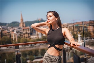 Posing of a young woman on the terrace of a hotel looking at the city from above