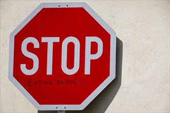 Stop sign with additional inscription eating Bacon