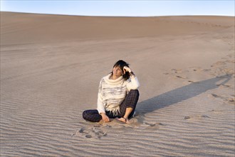 A woman is watching the sunset on a dune. Copy space