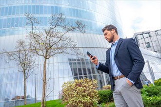 Male businessman or entrepreneur looking at mobile outside the office