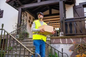 A young delivery man with a box and in a protective uniform at the delivery of the online order