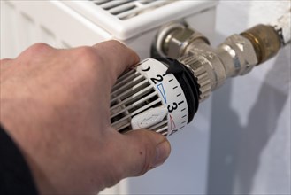 Man's hand turns thermostat