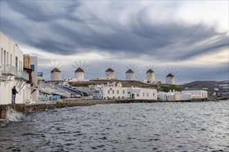 White Cycladic houses on the shore with windmills of Mykonos