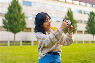 Asian young woman photography with a vintage photo camera visiting a city park