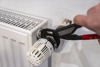 Hand with pliers on radiator thermostat
