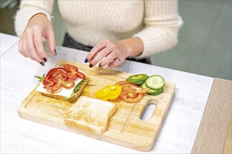 Unrecognizable person cooking a vegetable sandwich in the kitchen at home. Placing the red pepper