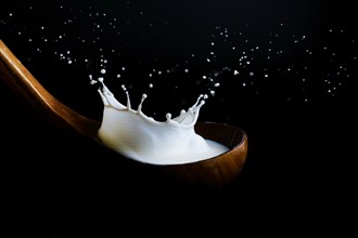 Milk splashing on a wooden ladle