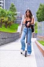 Young woman in the city with an electric scooter talking on the phone smiling