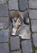 A miniature floor sculpture of a hand and a female titmouse on the Oudekerksplein