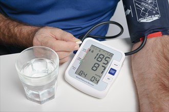 Older man with beard taking a pill after taking his blood pressure at home