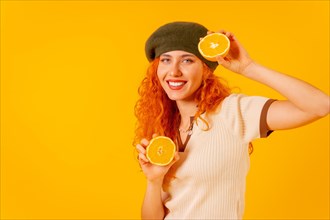 Redhead woman holding an orange over isolated yellow background