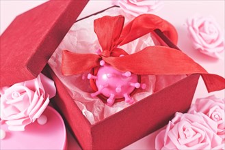 Valentine's day during Corona pandemic concept with virus model wrapped in ribbon in red gift box