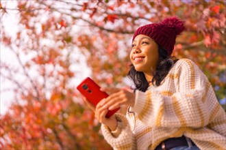 Portrait of an Asian woman in autumn with a mobile in a forest of red leaves