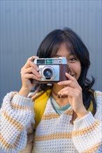 Portrait of a young Asian woman photographing with a vintage photo camera